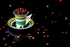 Roasted coffee beans beside a steaming cup