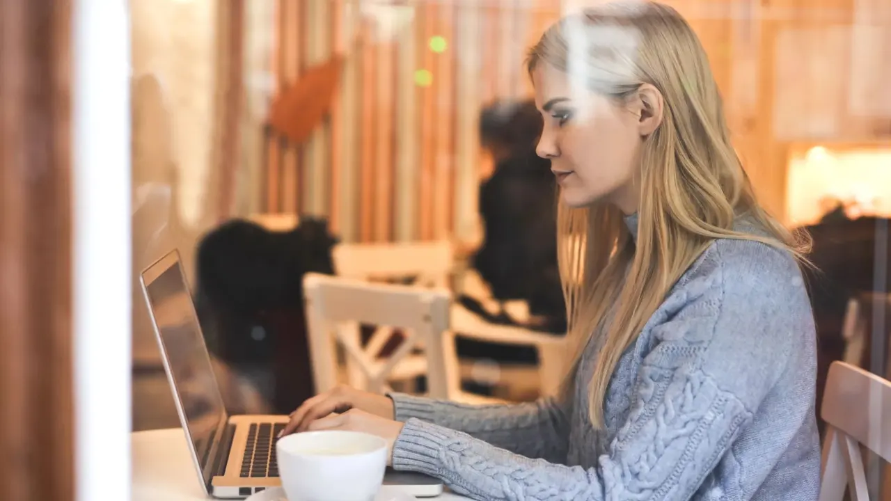 A blogger typing on a laptop beside a cup of coffee